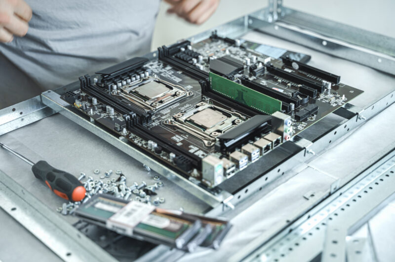 Dual-socket AI server motherboard being assembled with stainless steel CNC screws and precision mounting brackets.